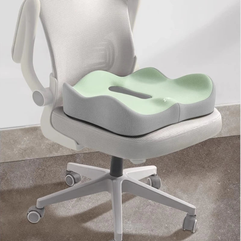 A light gray ergonomic seat cushion with a mint green insert is shown on a white office chair.