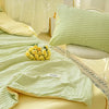 A light green Korean style seersucker summer quilt set with yellow pillows and a decorative lace trim.