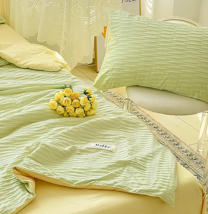 A light green Korean style seersucker summer quilt set with yellow pillows and a decorative lace trim.