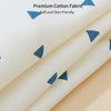 Close-up of a cream cotton fabric with small blue triangular patterns, showing the texture and softness.