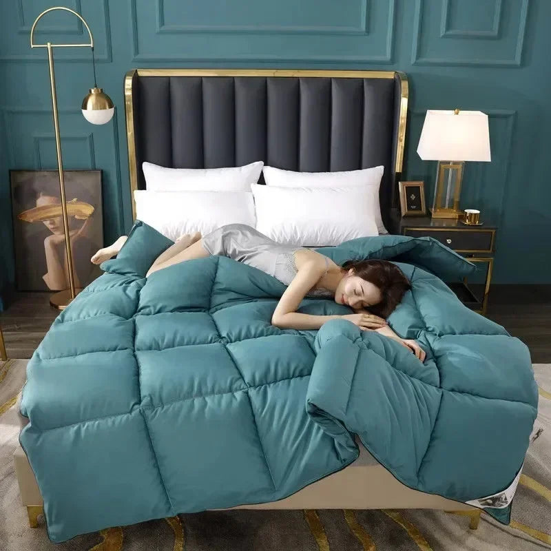 A teal goose down comforter duvet is displayed on a bed with dark gray bedding and gold accents.