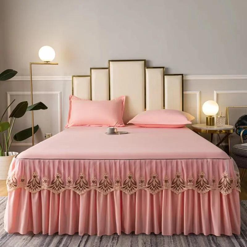 A pink embroidered cotton bedspread with matching pillows on a bed against a light gray wall.