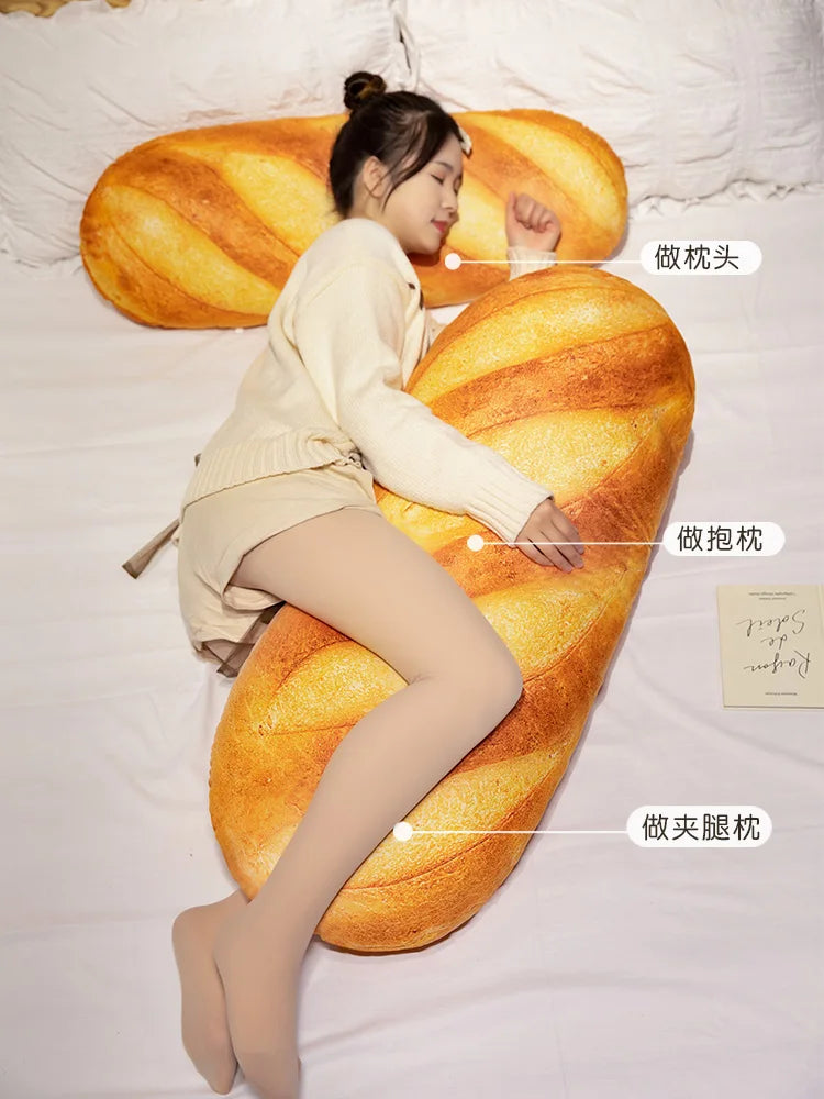 A woman is relaxing on a large, golden-brown plush baguette pillow in a bedroom setting.