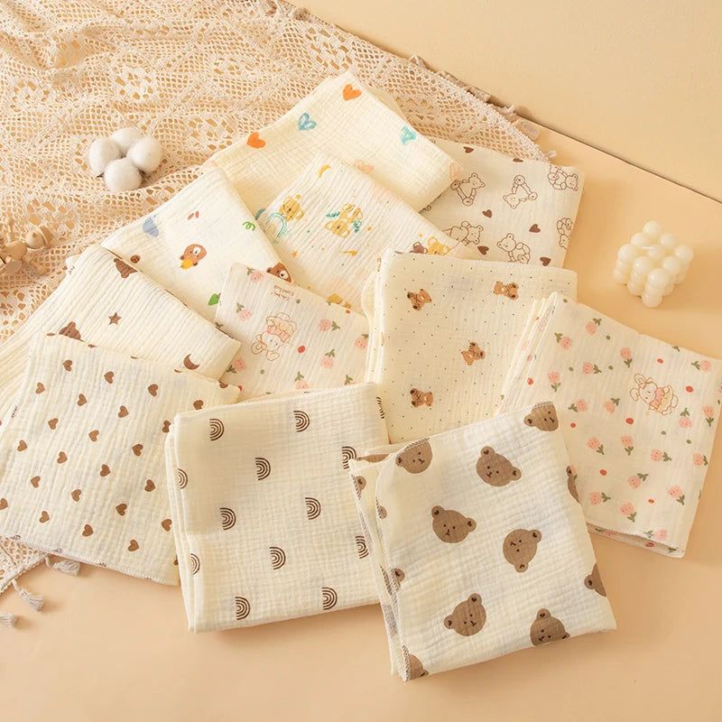 A collection of soft double-layer cotton baby swaddle blankets in cream and beige tones arranged on a light background.