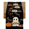 Black Halloween table runner featuring a pattern of white ghosts, pumpkins, bats, and cats.