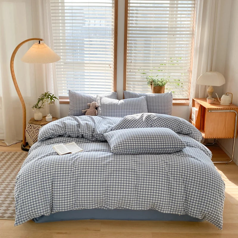 A bed dressed with a blue and white plaid duvet cover and matching pillowcases in a bright bedroom.