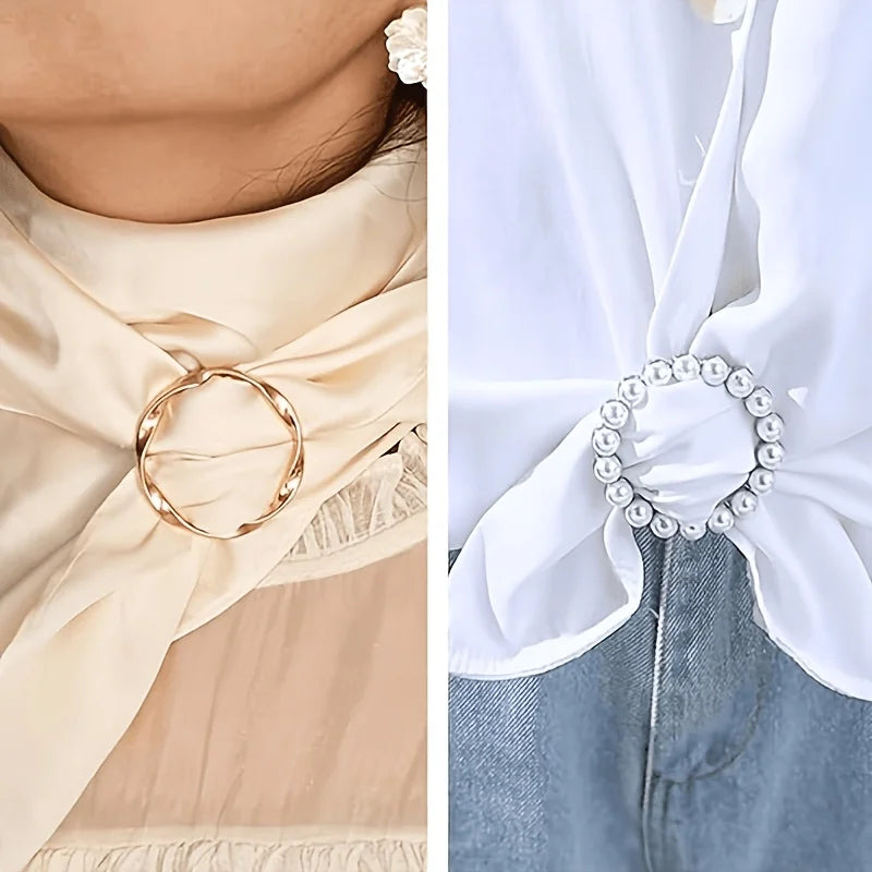 A close-up of an elegant gold metal scarf tied around a light beige dress and a pearl bracelet clip on denim fabric.