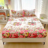 A floral print fitted bed sheet displayed on a white bed with sheer curtains and light wood flooring.