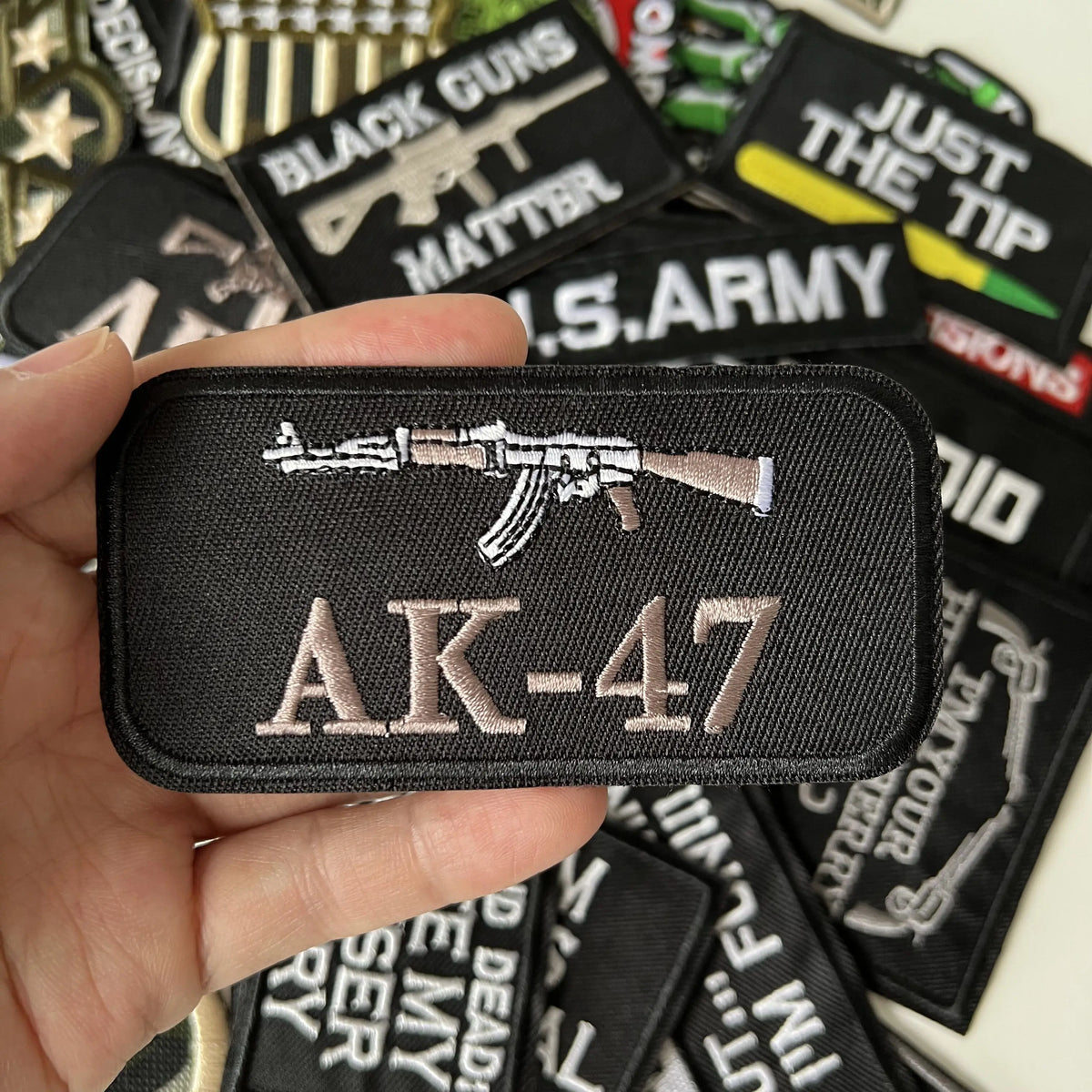 A black iron-on patch featuring the AK-47 silhouette and text on a hand.