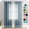 A set of gray sheer tulle window curtains hanging in a white frame against a light wall.