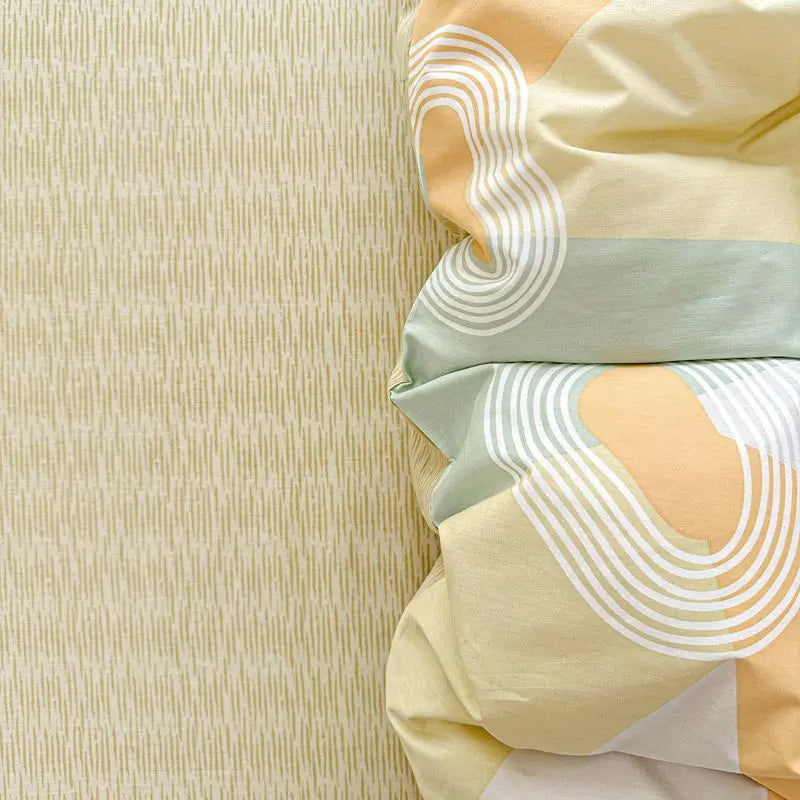 A close-up of a light yellow and sage green 100% cotton duvet cover featuring striped patterns.