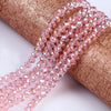 Pink faceted rondelle glass beads threaded onto a brown fabric ribbon for crafting
