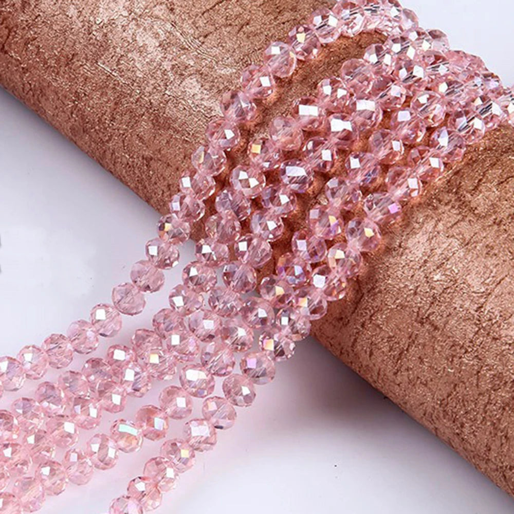 Pink faceted rondelle glass beads threaded onto a brown fabric ribbon for crafting