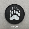 Black embroidered patch featuring a white paw print design on a gray background.