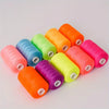 A collection of ten brightly colored polyester sewing thread spools arranged diagonally on a white surface.