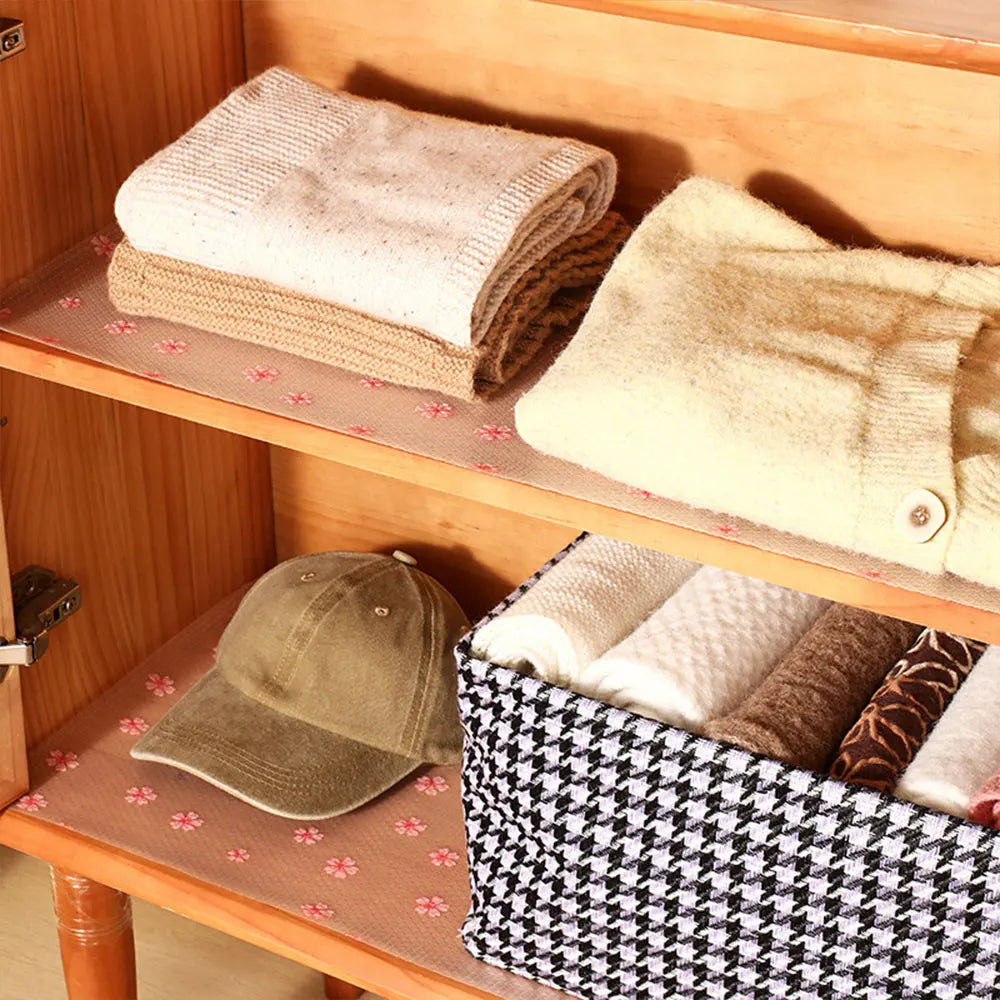 Reusable fridge and cabinet liner pads stacked on a wooden shelf with various fabric textures.