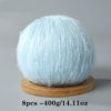 A ball of light blue mohair yarn resting on a wooden base.