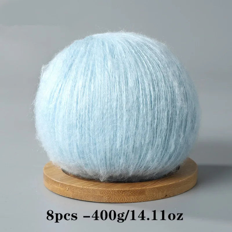 A ball of light blue mohair yarn resting on a wooden base.