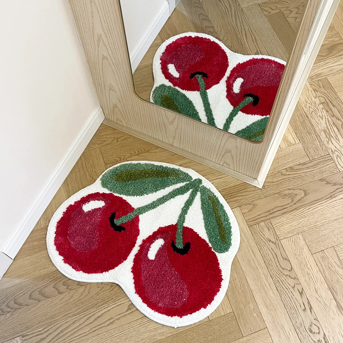 A red and green tufted area rug shaped like a fruit, displayed in a wooden frame.