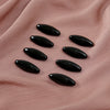 Eight black plastic safety pins arranged on a pink fabric background.