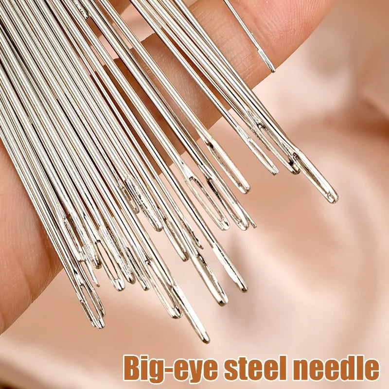 A hand holds a bundle of big-eye steel sewing needles for embroidery and crafting.