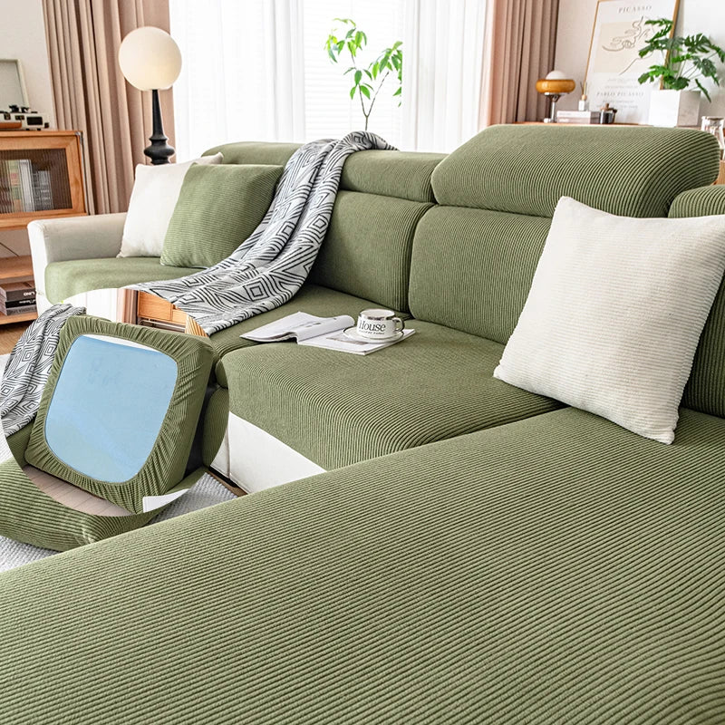 A plush olive green sofa cushion cover with striped fabric and white pillows on a light-colored sofa.