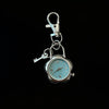 Silver pocket watch keychain featuring a clock face and a small key.