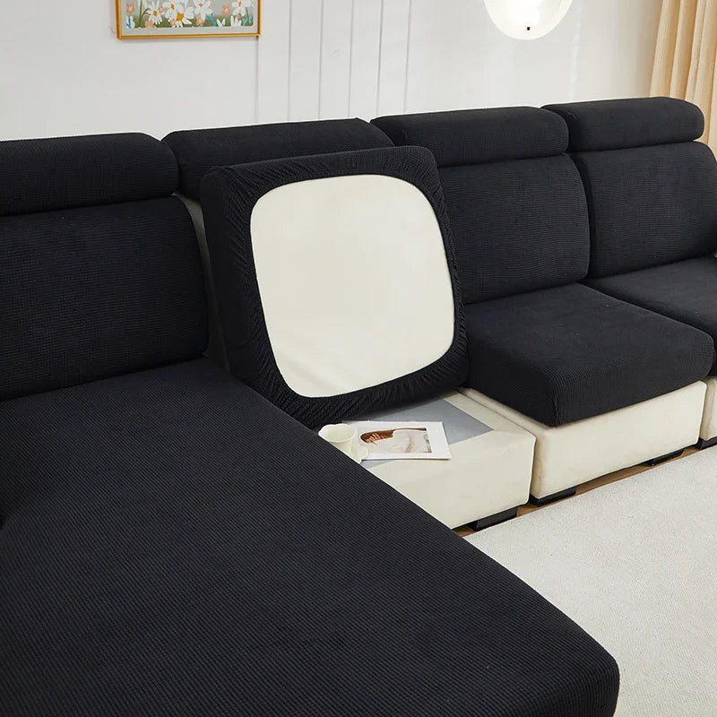 A black sofa cushion slipcover with a light cream accent, shown in a modern living room setting.