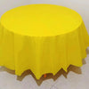A bright yellow round plastic disposable table cover on a white surface.