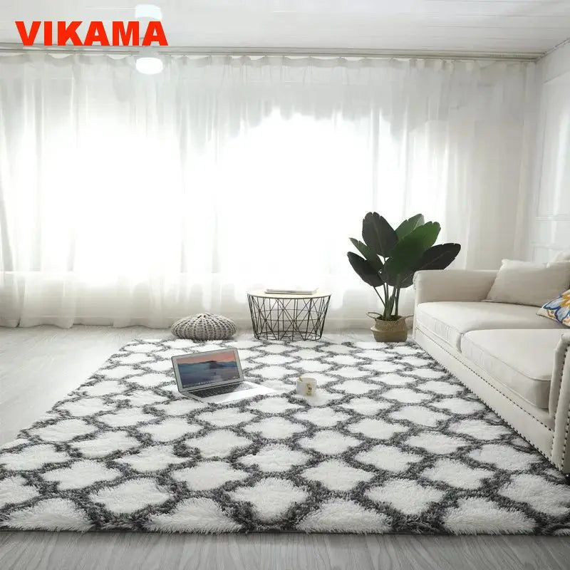 A geometric plush area rug with a black and white pattern placed on a light wooden floor in a bright living room.