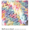 A close-up of fluffy, multi-colored hand-knitted yarn in pastel shades like pink, yellow, blue, and purple.