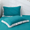 Teal ruffled princess pillowcases with white trim on a bed