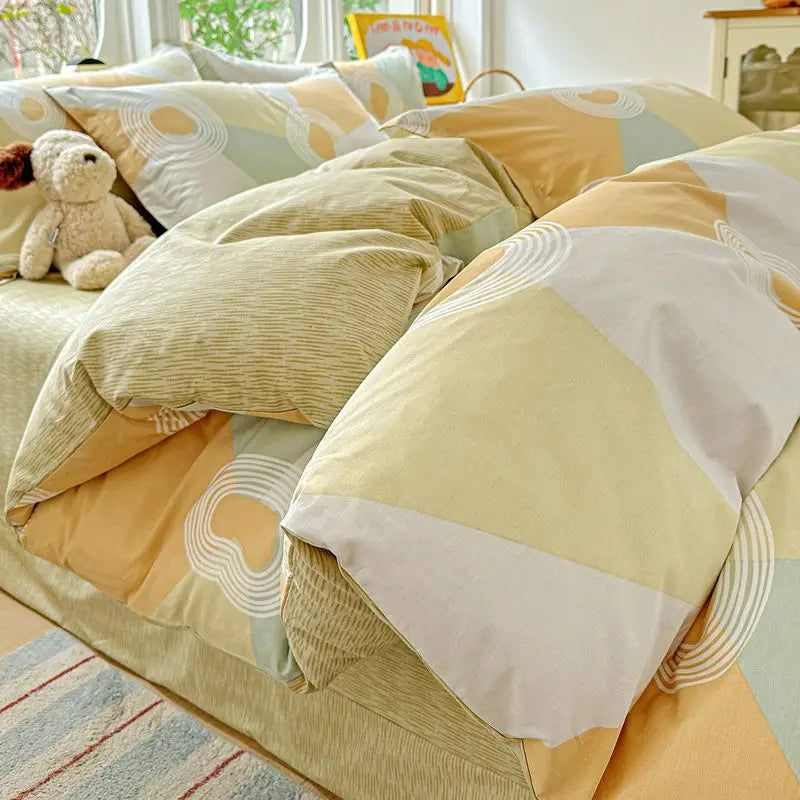 A beige and white duvet and pillow set featuring geometric patterns and a teddy bear plush toy.