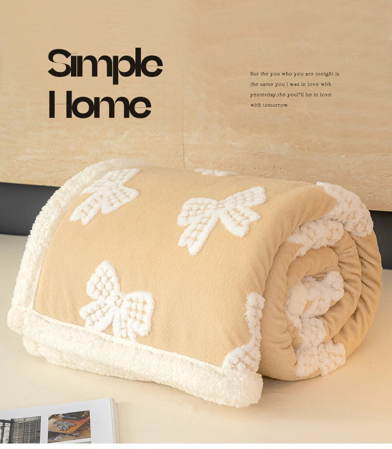A rolled thick jacquard lambswool blanket in beige with white butterfly patterns resting on a light surface.