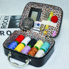 An open black portable sewing kit box showing various threads, a needle, and scissors on an orange leopard print background.