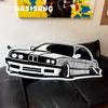 A black and white graphic of a classic car is displayed on a black leather sofa.