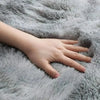 A hand rests on a soft gray faux fur rug.