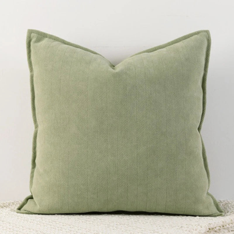 A solid sage green chenille throw pillow with a pointed shape.
