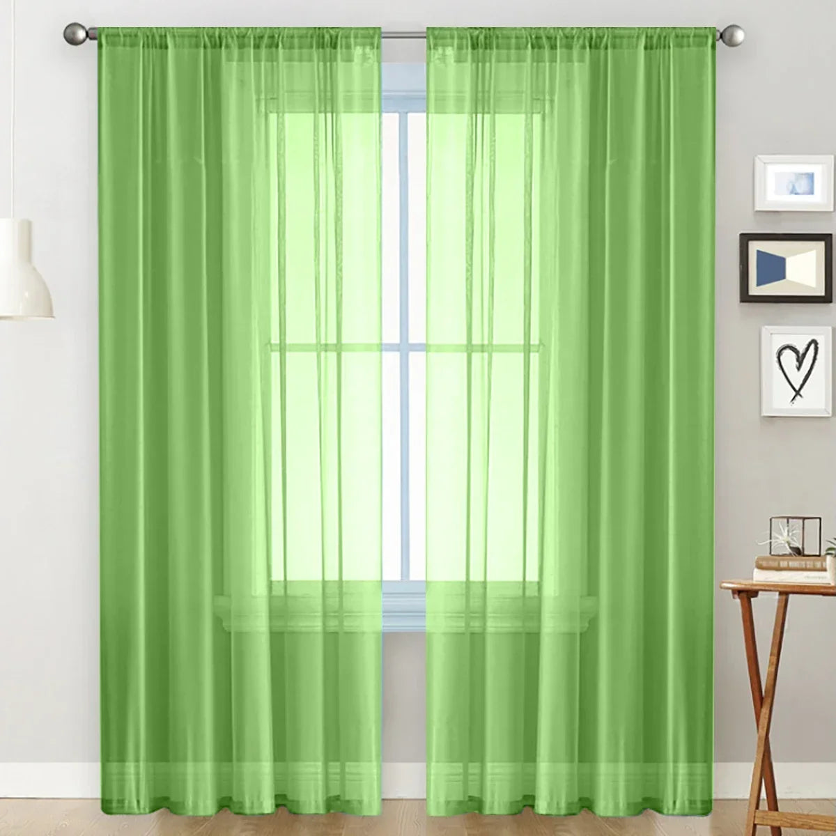 A pair of sheer lime green curtains hanging on a rod, showing a bright window view.