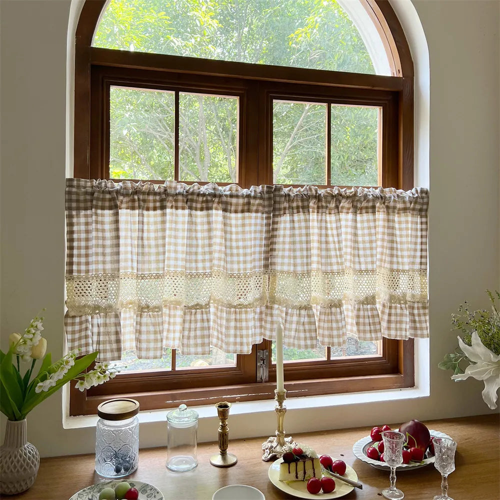 Beige gingham crochet lace curtain valance hanging over a wooden window frame.