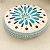 A round cushion with a bohemian pattern featuring teal, black, and cream dots and petals for floor seating.