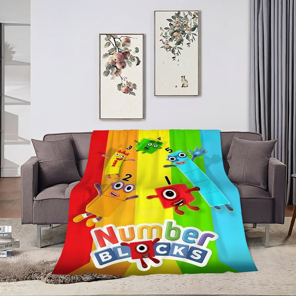 A colorful throw blanket featuring cartoon animals and the text Number Blocks displayed on a sofa.