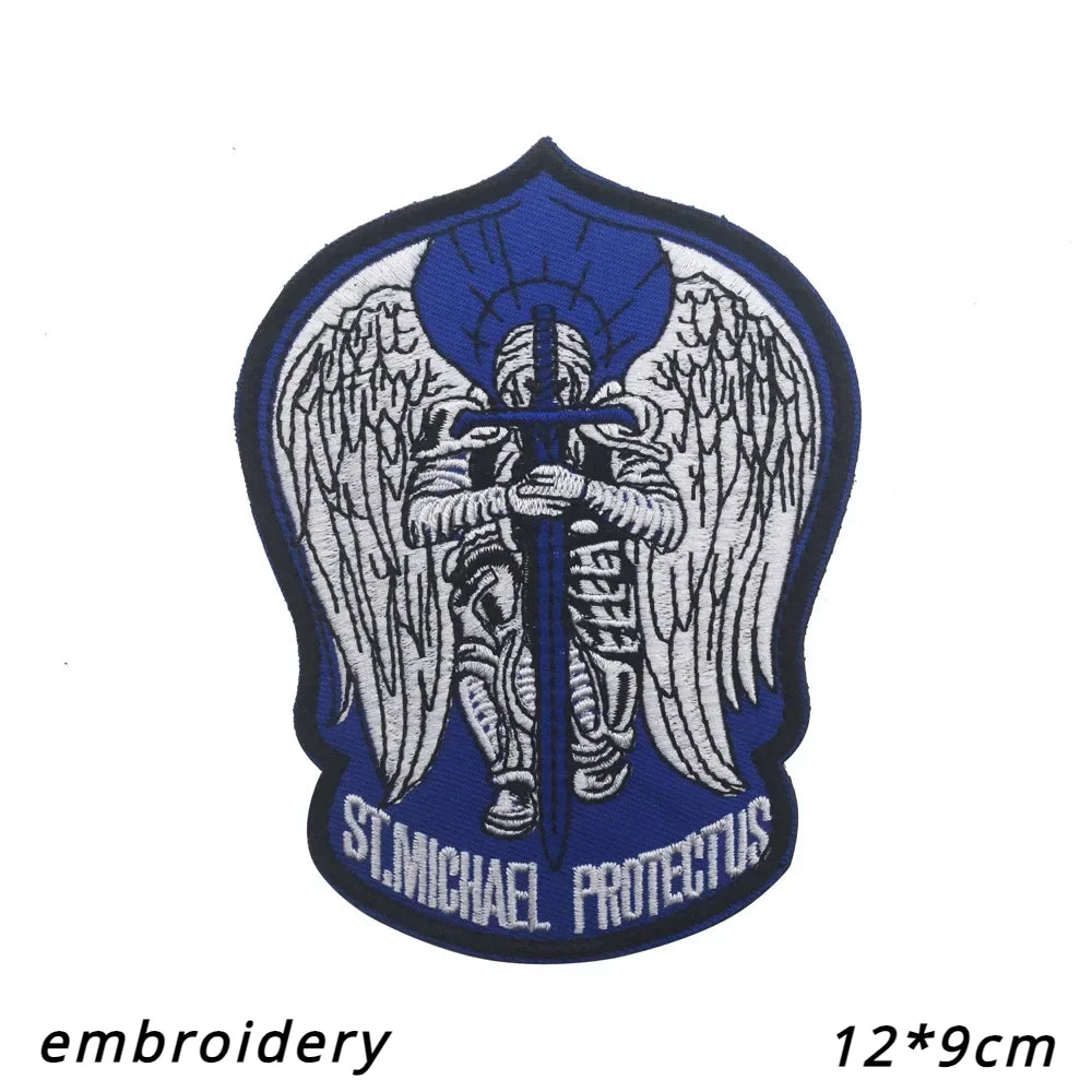 An embroidered patch featuring a winged figure with a sword and halo on a blue background.
