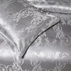 Silver satin duvet cover featuring intricate white floral embroidery and damask pattern.