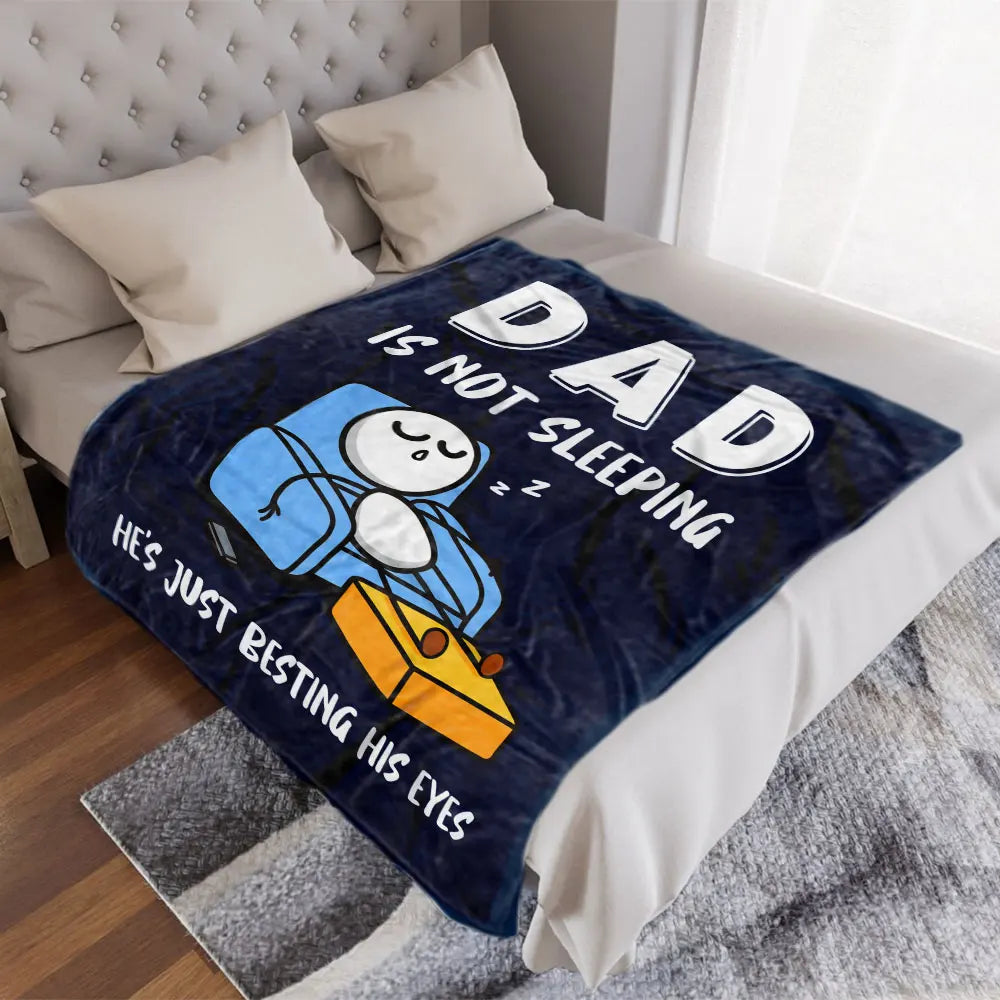 A dark blue blanket featuring a cartoon illustration of a sleeping owl with the text Is Not Dad Sleeping
