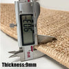 A silver caliper measuring a thickness of 9mm against a natural sisal jute rug.