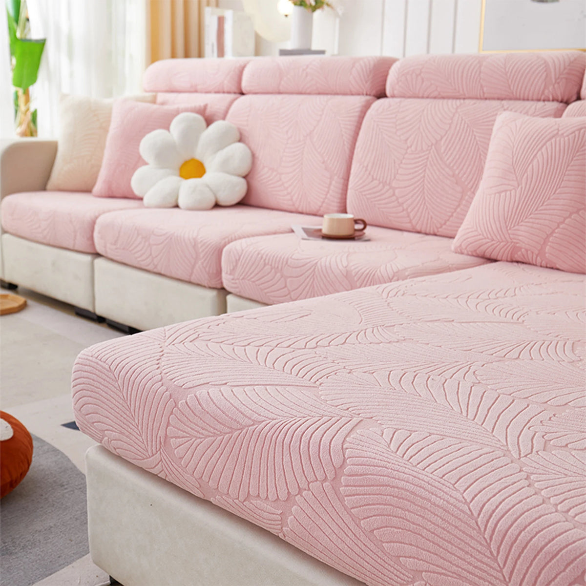 A pink leaf jacquard stretch sofa cover displayed on a light-colored sofa with white decorative pillows.