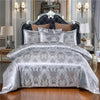 A luxury royal style duvet cover set featuring silver gray fabric with intricate damask patterns on a bed.