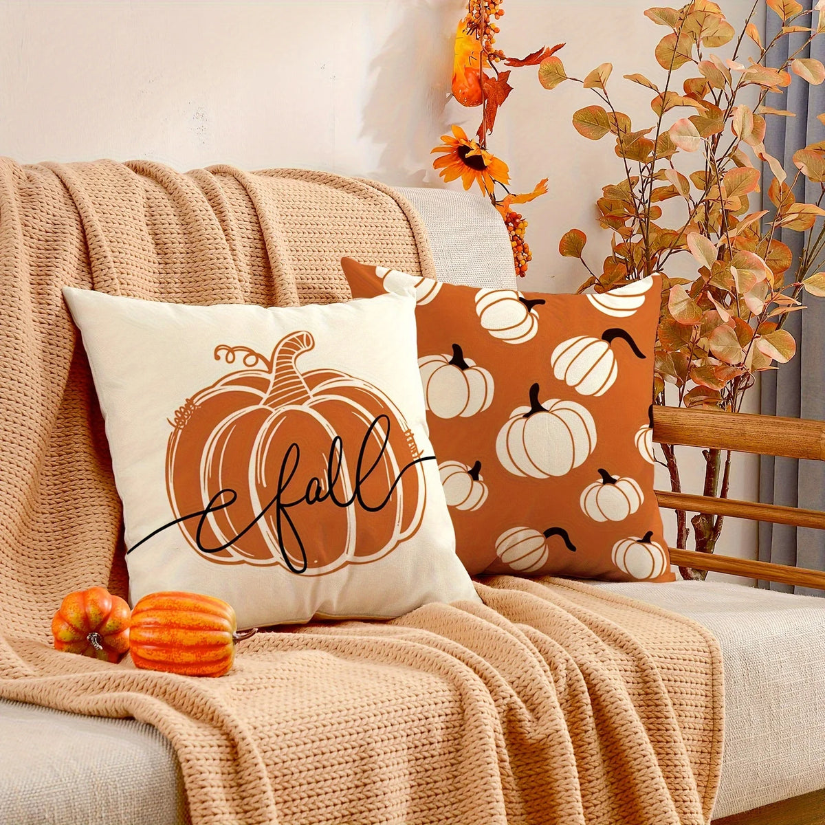 A set of vintage autumn pumpkin pillow covers in orange and cream tones displayed on a beige knitted blanket.