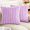 A pair of fluffy lavender faux rabbit fur cushion covers resting on a light-colored sofa.